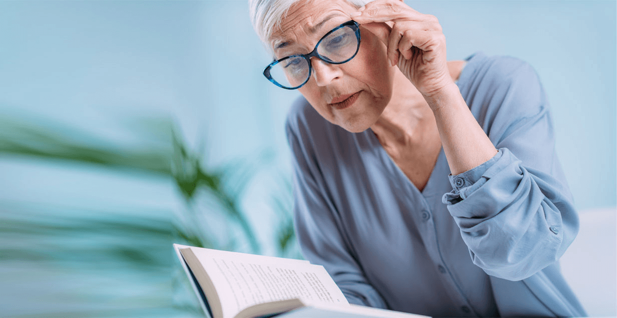 Presbyopic woman reading a book with her glasses on.